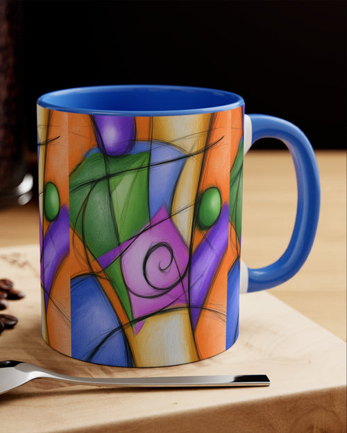A ceramic coffee mug with a vibrant, multicolored abstract stained-glass style print, featuring a bright blue handle and interior. The mug is styled on a wooden board next to a spoon, coffee beans, and a macaron, with a blurred coffee bean jar in the background.
